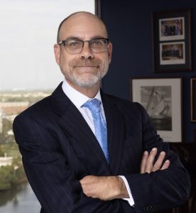 Smiling man wearing glasses, arms crossed