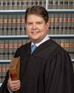Smiling man wearing judicial robe holding a book