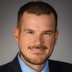 man with facial hair smiling at the camera