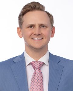 a smiling man wearing a pink tie