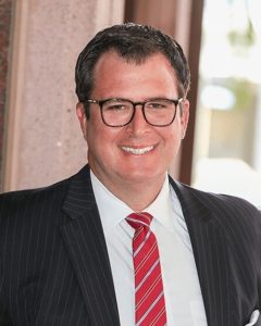 a man wearing glasses and a red tie smiling for the camera