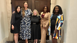 a group of women in business attire smiling at the camera