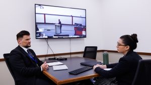 two people sitting at a table in front of a television screen